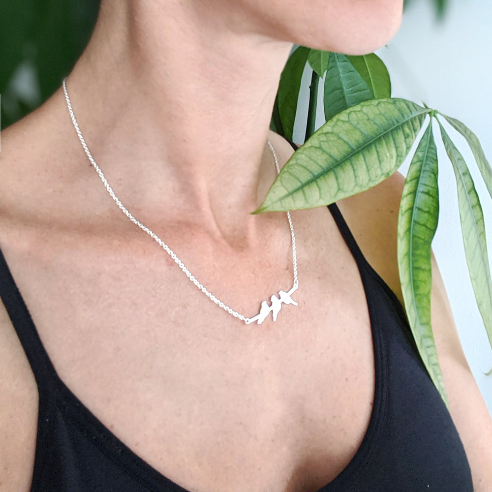 
                
                    Load image into Gallery viewer, Silver Three birds on a branch necklace on a model 
                
            